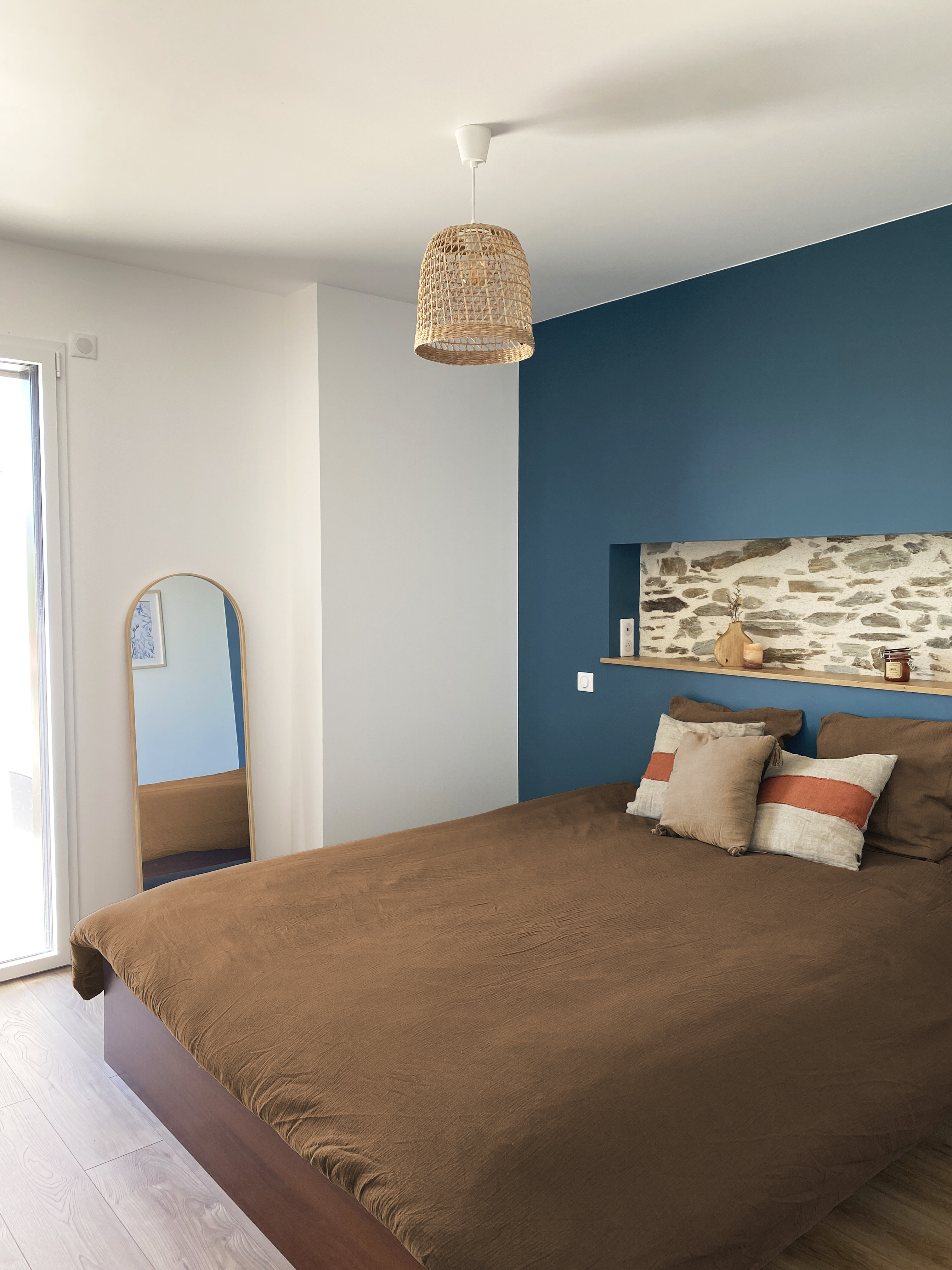 Chambre avec niche en pierre au-dessus du lit, mur bleu marine et décoration ambre — Projet Tremblay, réhabilitation complète