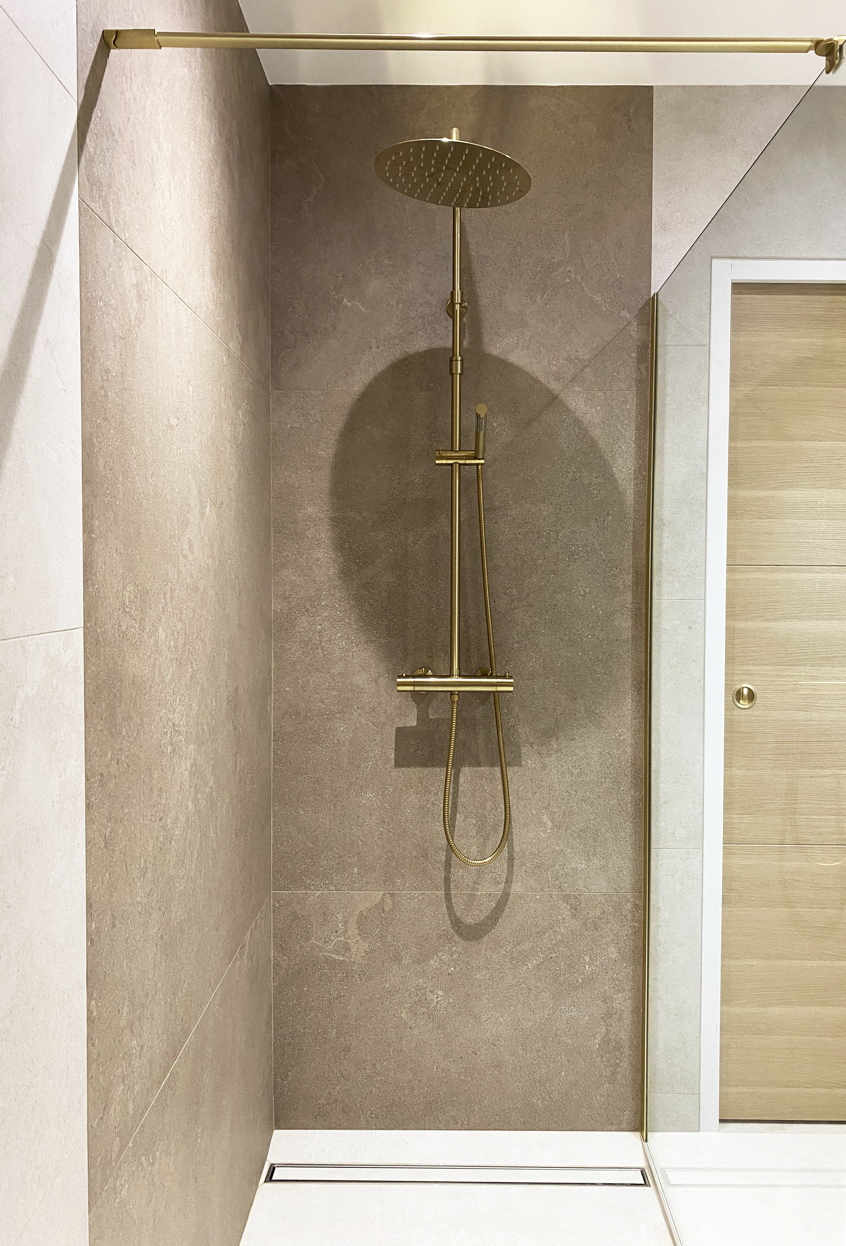 Douche à l'italienne, carrelage taupe, colonne dorée, paroi vitre Salle de bain bois et terracotta — Projet N&C, salle de bain rénovée